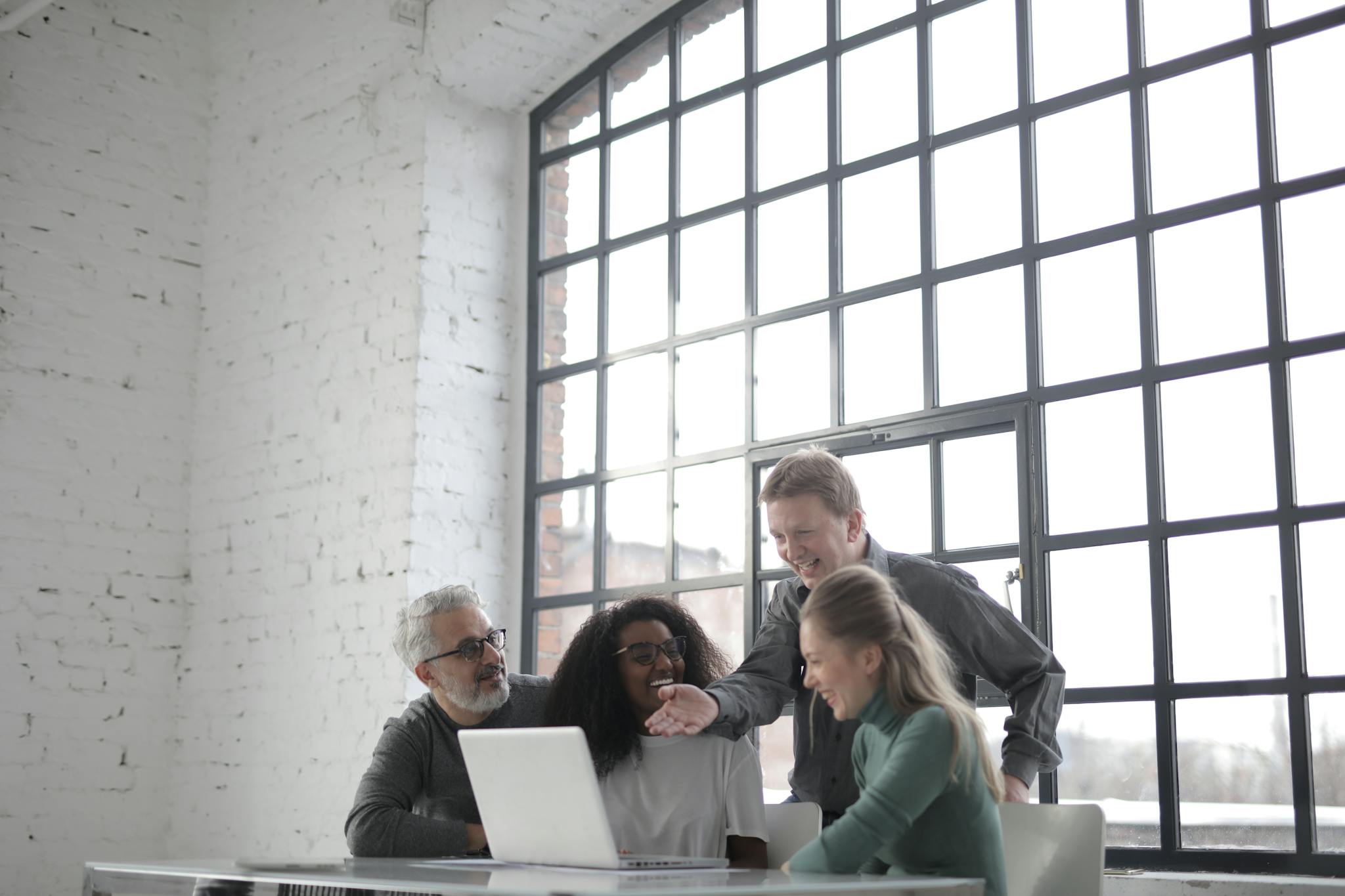 A diverse team joyfully collaborating in a modern office with ample natural light.